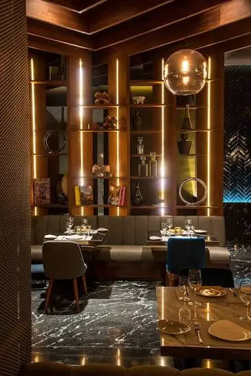 Restaurant bar in low light, copper columns rising past a mirrored back bar