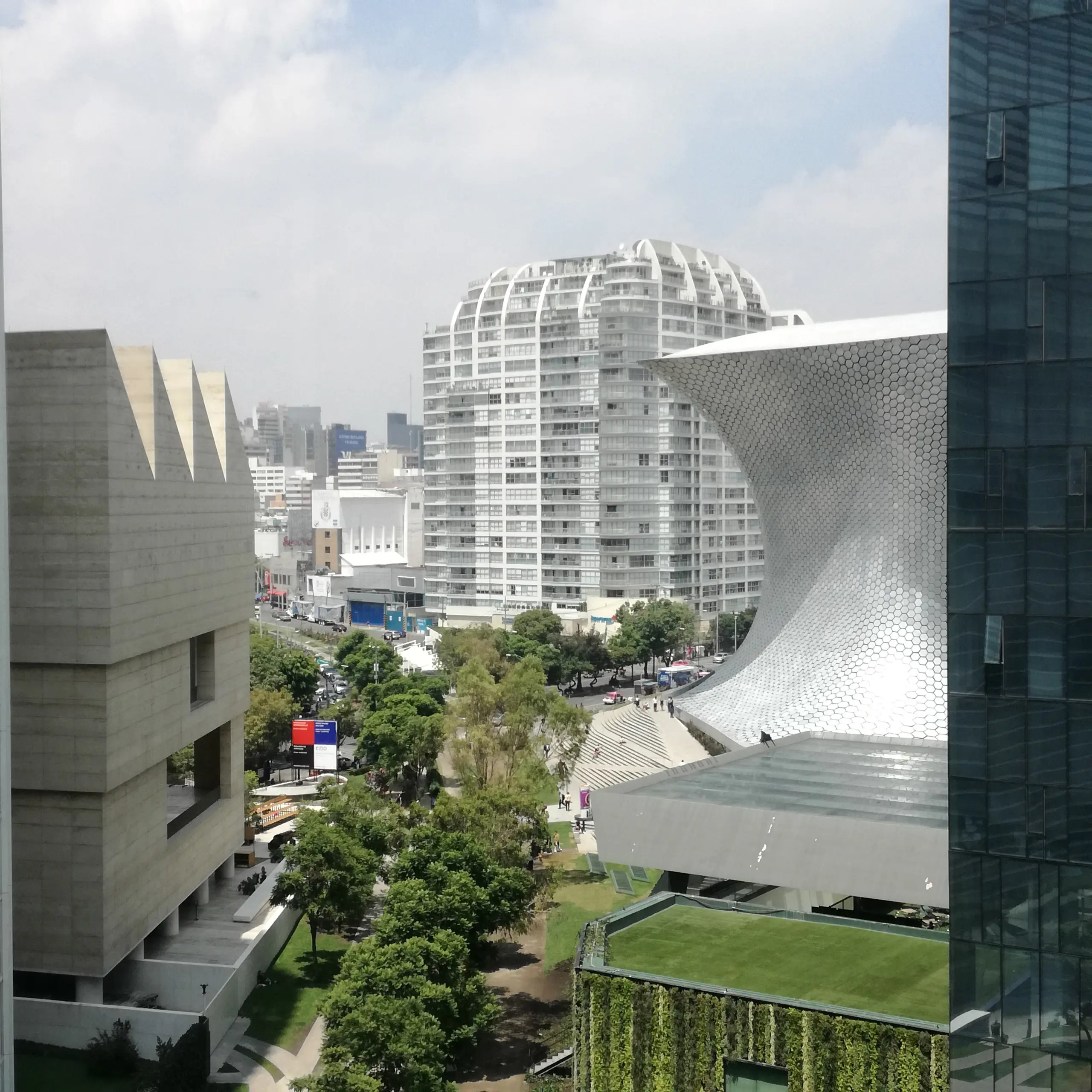Museo Soumaya's silver hourglass form seen from above, Museo Jumex and the Mexico City skyline behind it