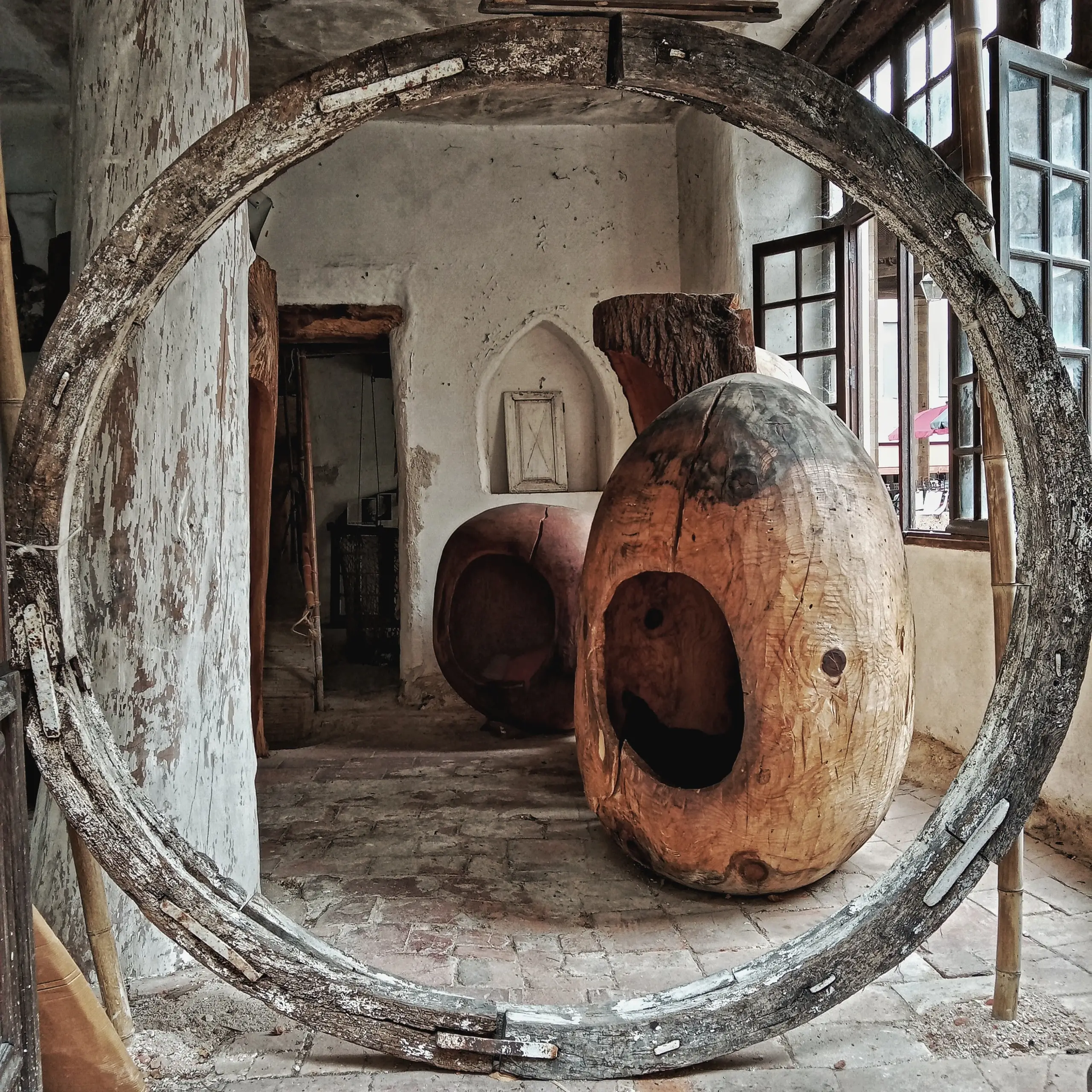 Derelict industrial interior, a large weathered wooden vessel resting inside a rusted circular ring