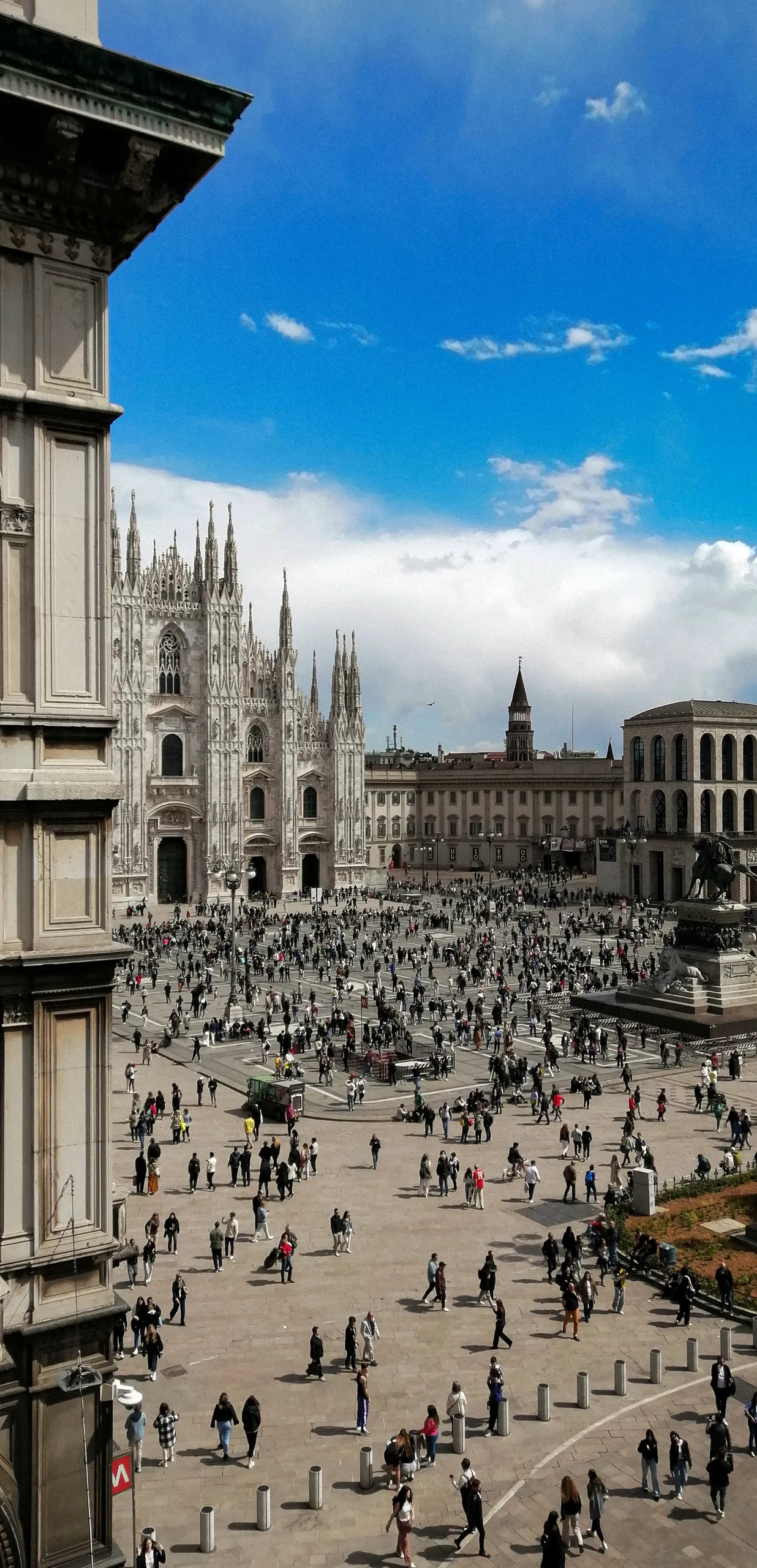 Piazza del Duomo, Milan, seen from above — the cathedral's spires at left and the crowd scattered across the square below