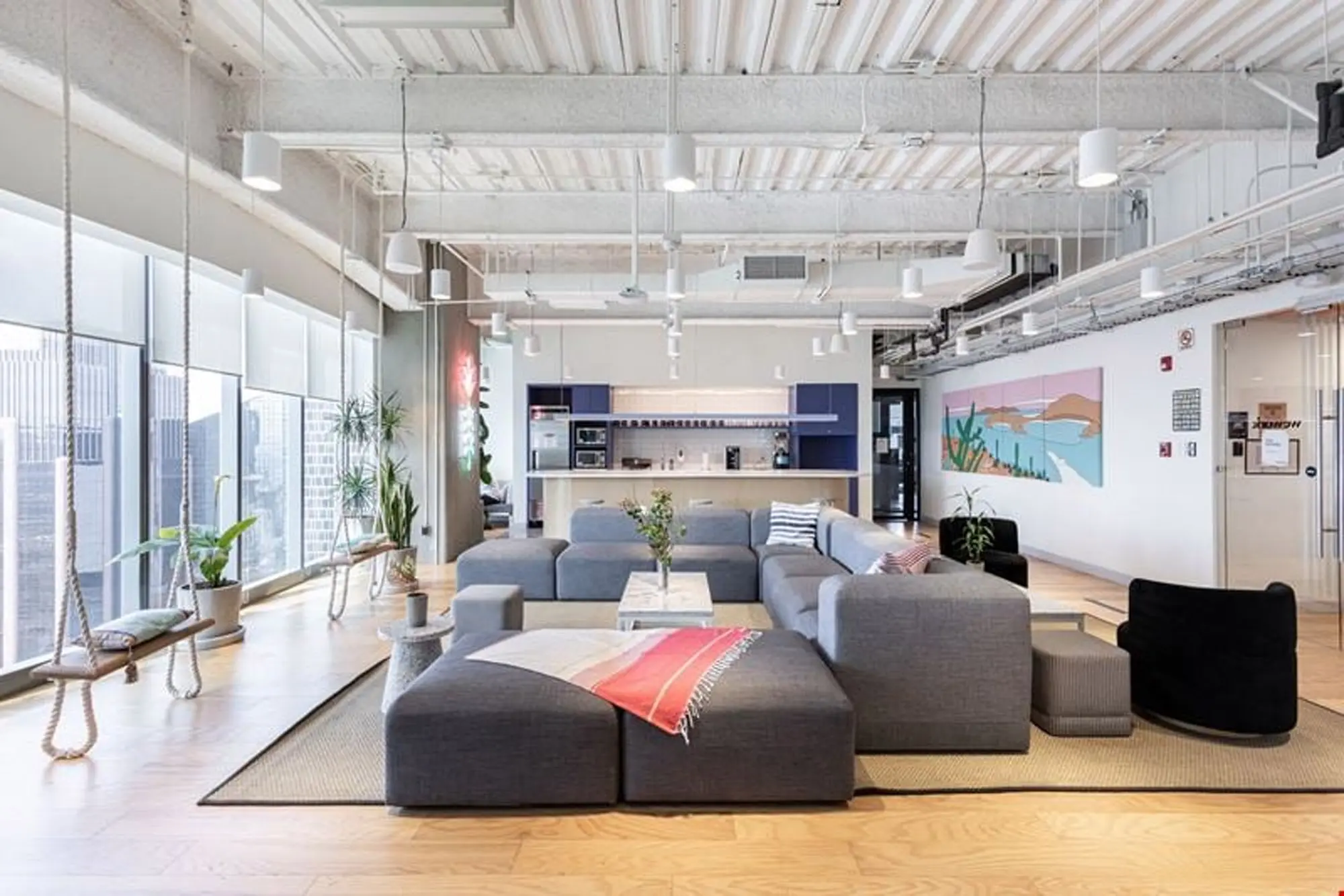 Open-plan office lounge with soft seating under an exposed services ceiling