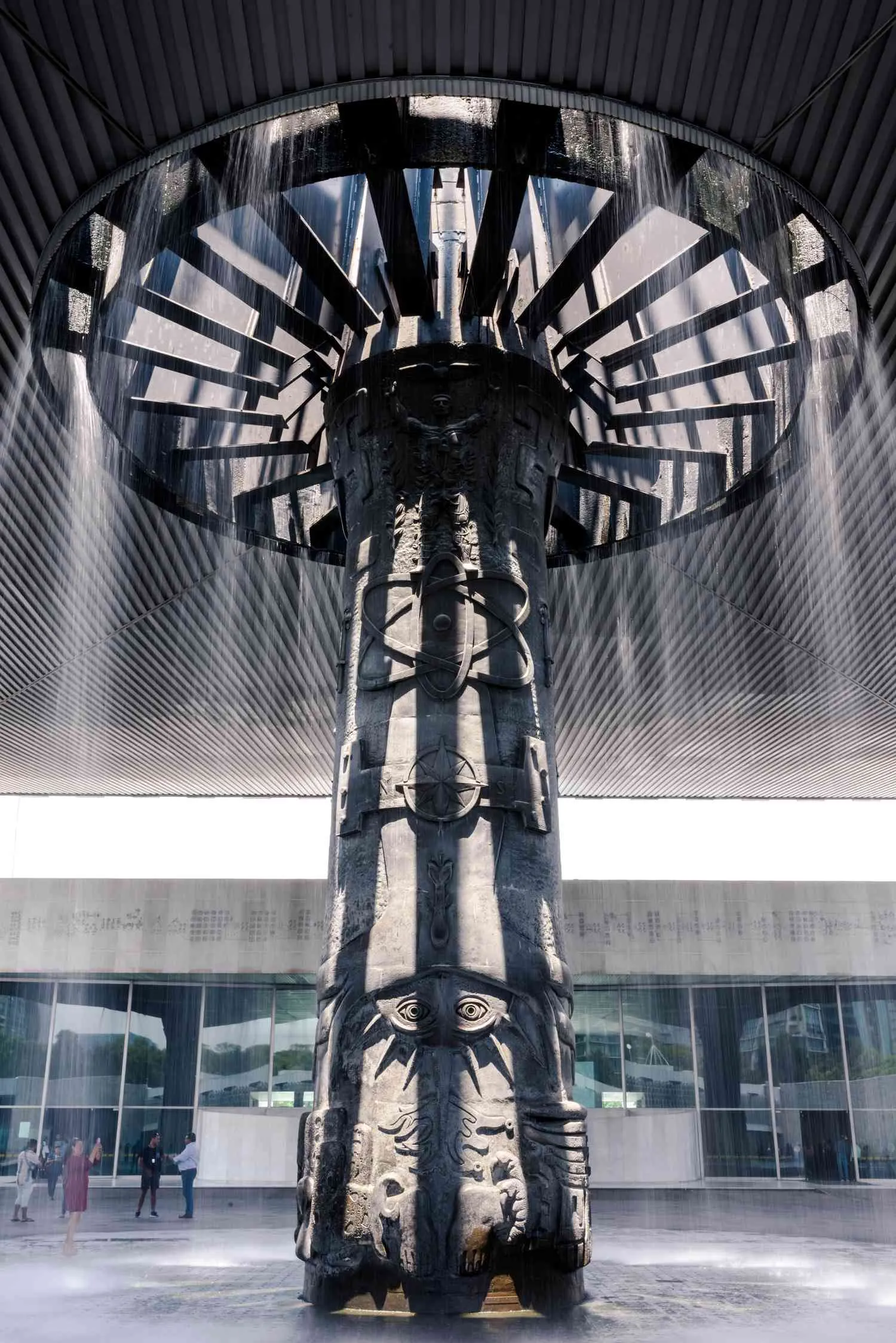 Looking up the column of El Paraguas — the radiating steel ribs of the canopy above, and the water falling in a fine curtain all around it