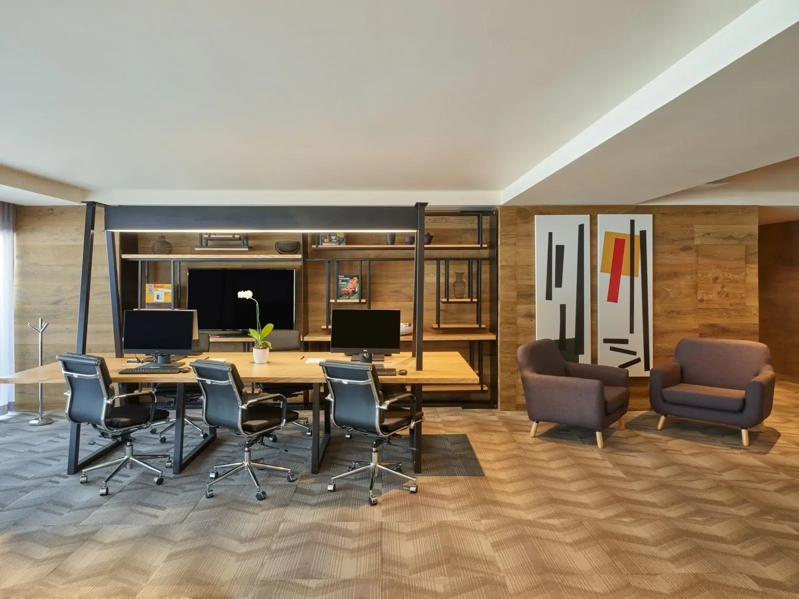 Hotel lobby lounge — low armchairs and a long communal table under a timber ceiling
