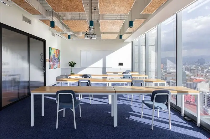 Glazed meeting room with a long white table and a city view beyond