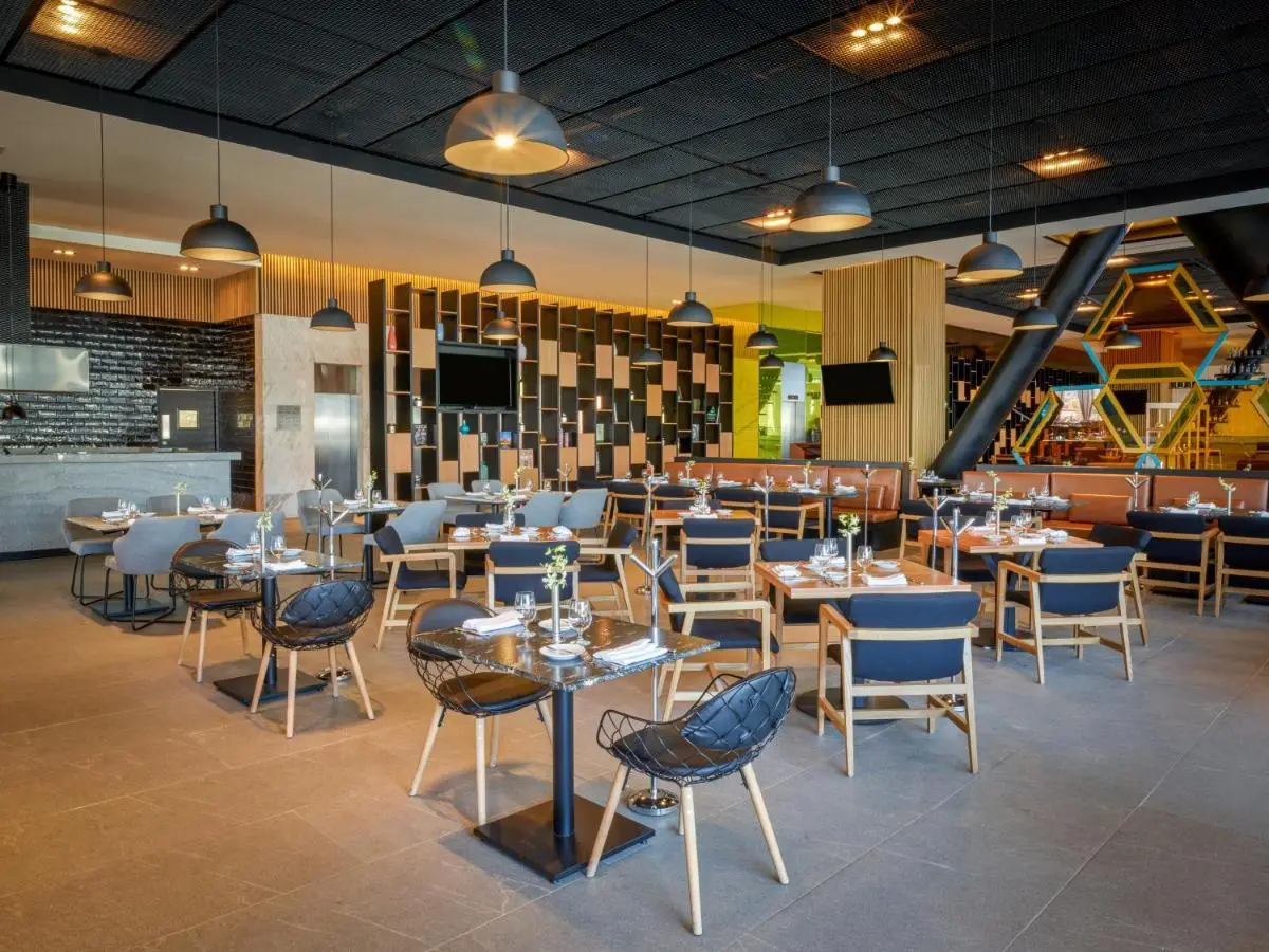 Hotel restaurant seating — blue upholstered chairs and pendant lights over pale tables