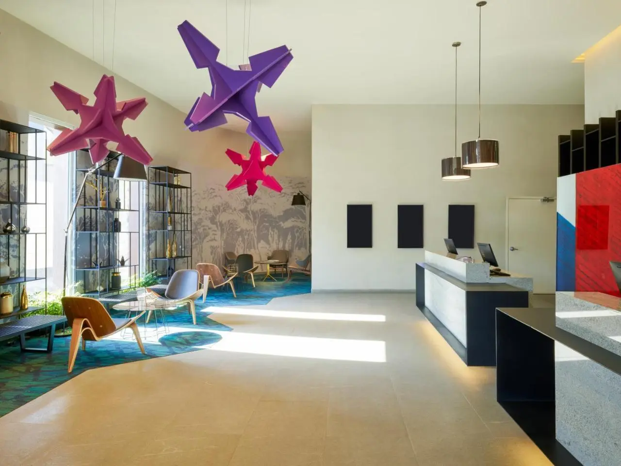 Hotel lobby with brightly coloured star sculptures suspended above a pale seating area