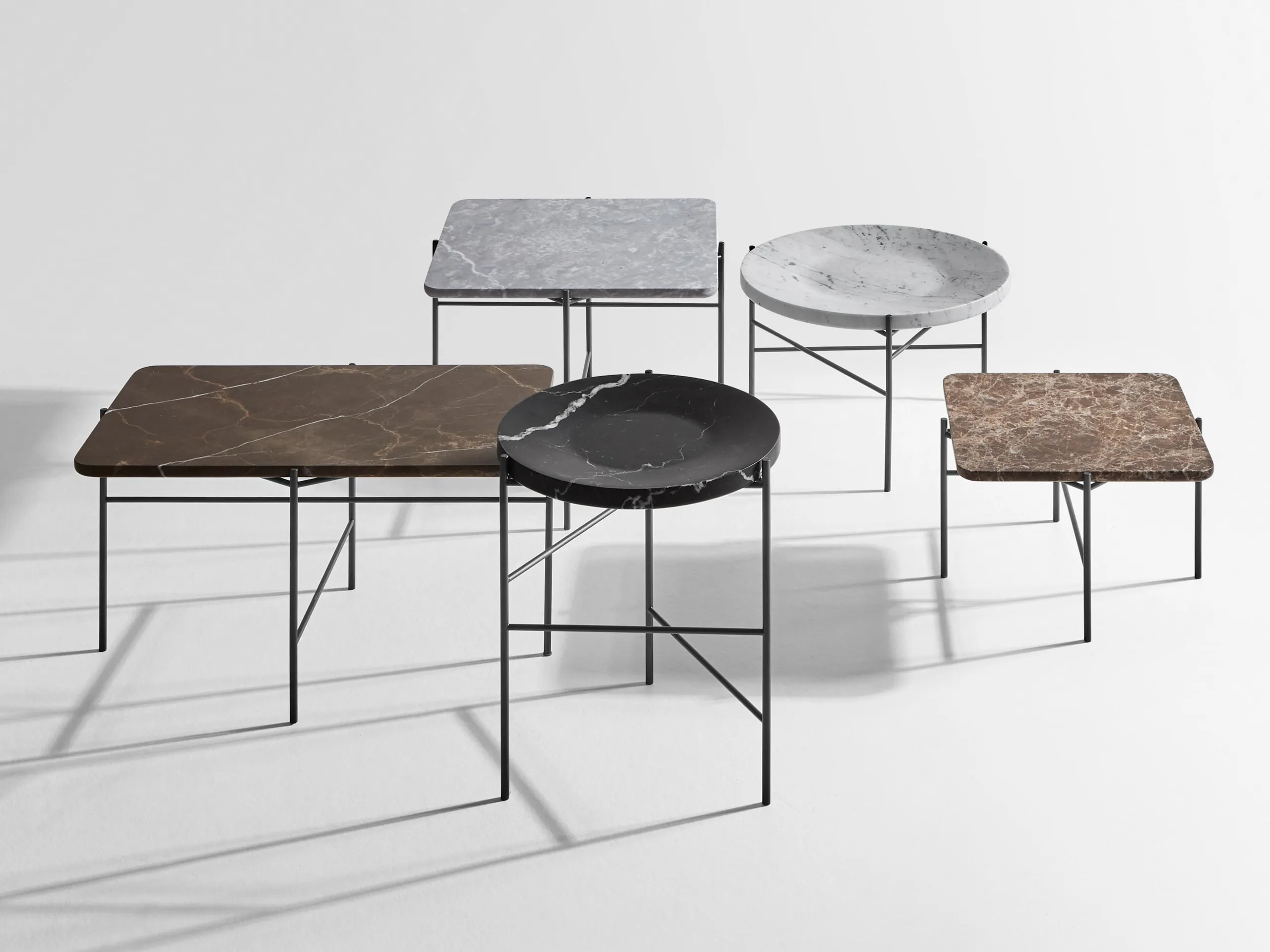 The table cluster in a dark interior, seen from further back — the tops reading as a single stepped surface