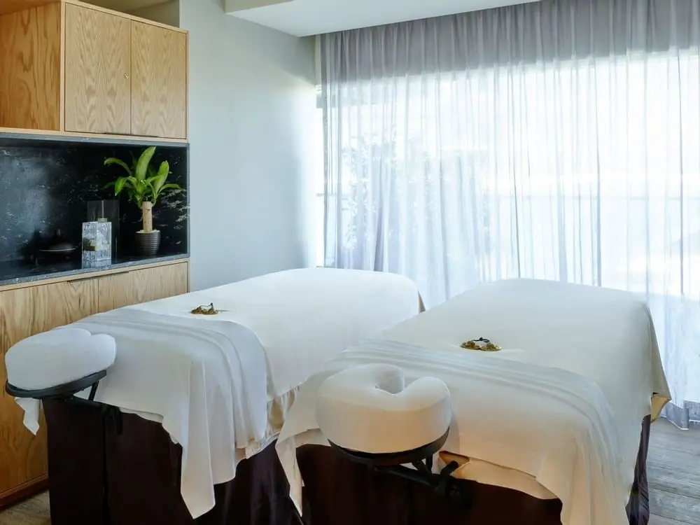 Spa treatment room with paired massage beds and warm stone walls