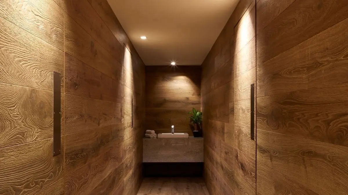 Spa corridor lit from a concealed cove, stone-clad walls narrowing toward a basin at the end